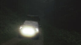 Foto von Alex Sobotta: Ein 2025 Subaru Forester mit leuchtenden Scheinwerfern fährt durch einen dunklen, nebligen Wald auf einem schmalen Feldweg, umgeben von dichter Vegetation. Die Fotografie fängt dramatisches Licht und mystische Atmosphäre ein. A 2025 Subaru Forester drives with headlights on through a foggy, dense forest at night. Moody lighting enhances the cinematic look. Alex Sobotta Fotograf