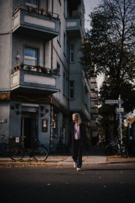 Schauspielerin Elisabeth Becker steht allein auf einer leeren Straße vor einem Berliner Altbau, Porträt in Berlin von Alex Sobotta Alex Sobotta Fotograf
