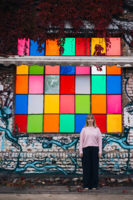 Elisabeth Becker vor einer bunten Wand aus farbigen Fensterflächen und Graffiti in Berlin Alex Sobotta Fotograf