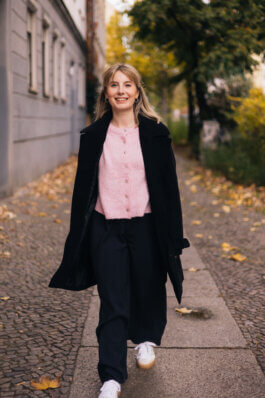 Elisabeth Becker geht über einen Berliner Gehweg mit Herbstlaub auf die Kamera zu Alex Sobotta Fotograf