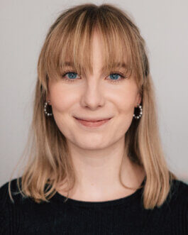 Headshot von Elisabeth Becker mit leichtem Lächeln vor hellem Hintergrund Alex Sobotta Fotograf